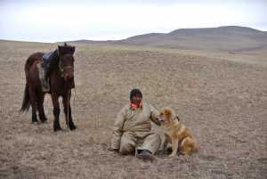 In this photo taken Nov. 13, Chulunjav Bayarsaikhan poses for photos with Hassar, a shaggy, 11-month-old bankhar puppy, in Tuv Province, Mongolia.