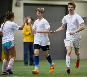 MC Dreidel's Jackson Norberg, center, celebrates with teammates Abby DeRocher, left, and Corbin Mitchell after his score against the South Pole Elves during their high school division game in the Holiday Cup at the Dimond Park Fieldhouse on Tuesday.