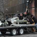 Workers load the remains of a small plane that crashed into two office buildings in downtown Anchorage on Tuesday.
