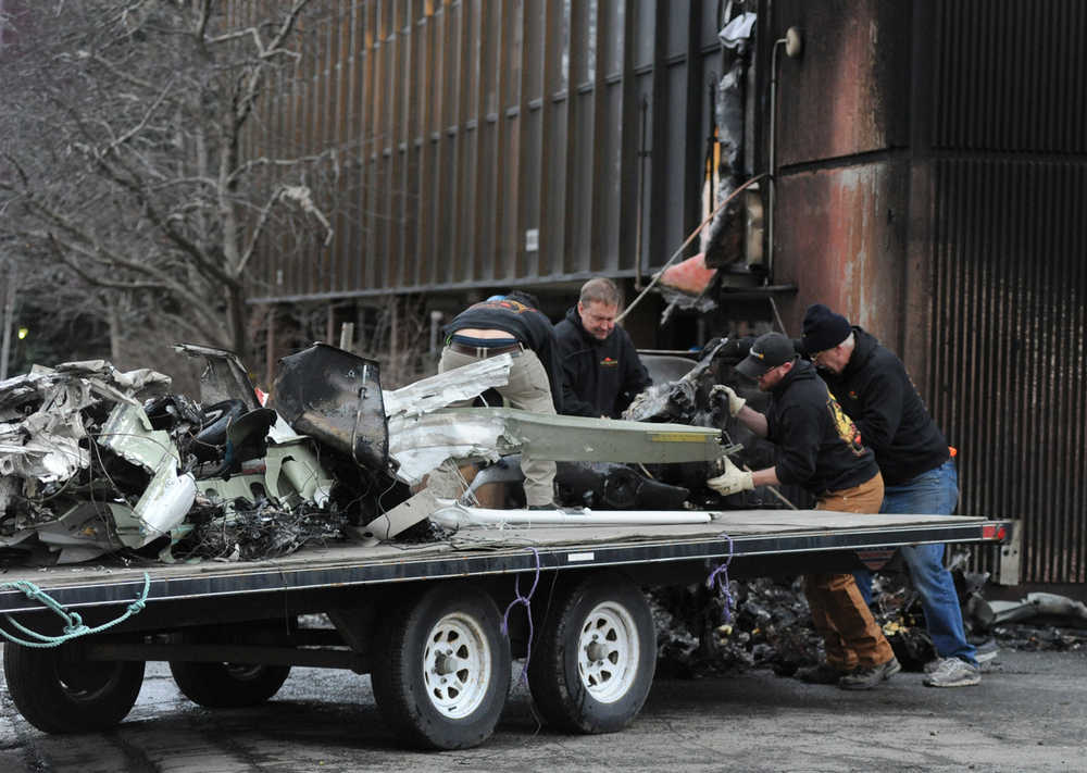 Workers load the remains of a small plane that crashed into two office buildings in downtown Anchorage on Tuesday.