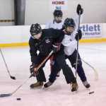 Juneau-Douglas High School assistant hockey coach Matt Boline, left, and Kaleah Haddock demonstrate a puck possession drill.