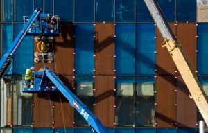 PCL Construction employees install panels onto the front of the State Library, Archives, and Museums building in October.