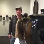 University of Alaska Southeast associate professor of art Jeremy Kane stands with some of his creations for "Surface," a show at the Juneau-Douglas City Museum. Kane, whose work is usually retro and Americana-focused, went back to his wood-firing roots for this particular show. Colors, and variations in surface texture, in the pieces are created by what he put in the kiln when they were being fired.