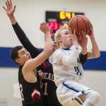 Thunder Mountain's Chase Saviers cuts through Juneau-Douglas' Treyson Ramos, left, and Bryce Swofford to shoot during their crosstown match up at TMHS on Friday. JDHS won 66-47.
