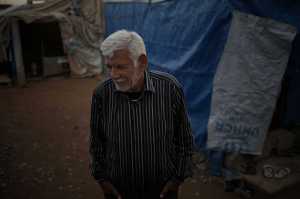 This  Monday, Jan. 11, 2016 photo shows  Ibrahim Mahmoud standing in Baharka refugee camp in Iraq's northern Kurdish region. At the age of 9, during the 1948 Israeli-Arab war he fled his native Haifa with his family to Iraq and he hasn't left ever since. The now 76 year-old never got rid of the refugee status. The last city he lived in was Mosul, until it got taken by the Islamic State group. Ibrahim and his family fled again, this time to the Northern Kurdish region of Iraq. (AP Photo/Bram Janssen)