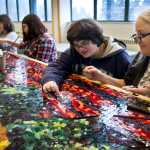 Artist Marianne Manning, right, works with seventh-graders Amanda Lamburt, center, Amy Budke and eighth-grader Claire Schumacker, left, on a three by eight-foot glass mosaic based on a painting by Dutch artist Vincent van Gogh at Dzantik'i Heeni Middle School on Wednesday. Manning is spending two weeks working with the middle school students on producing two glass mosaic panels as part of the Artist in the Schools Program.