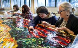 Artist Marianne Manning, right, works with seventh-graders Amanda Lamburt, center, Amy Budke and eighth-grader Claire Schumacker, left, on a three by eight-foot glass mosaic based on a painting by Dutch artist Vincent van Gogh at Dzantik'i Heeni Middle School on Wednesday. Manning is spending two weeks working with the middle school students on producing two glass mosaic panels as part of the Artist in the Schools Program.