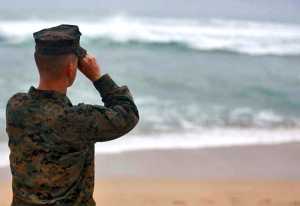 This Friday, Jan. 15, 2016 photo provided by the U.S. Marine Corps shows a Marine Officer attached to Marine Heavy Helicopter Squadron 463 uses binoculars to search for debris of a helicopter mishap in Haliewa Beach Park, Hawaii. Rescuers battled winds of up to 23 mph and waves up to 30 feet as they searched for 12 Marines who are missing after two helicopters they were in crashed off the Hawaiian island of Oahu.(Cpl. Ricky S. Gomez/U.S. Marine Corps via AP)