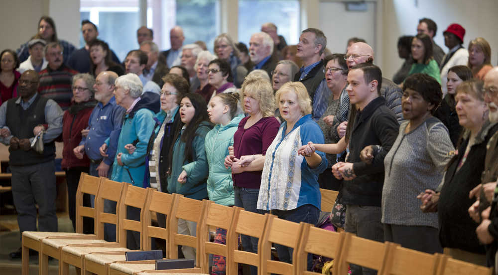 Community members hold hands as they sing "We Shall Overcome" during the Dr. Martin Luther King Jr. 2016 Community Celebration at the St. Paul's Catholic Church on Monday.