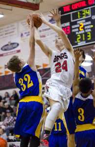 Juneau Douglas's Erik Kelly shoots against Kodiak's Louis Rochelan, left, and Billy Alcaide, right, during their game at JDHS on Friday. Juneau won 75-40.