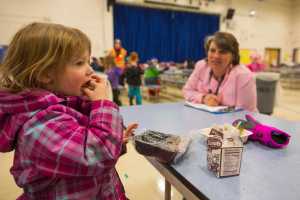 In this photo taken Jan. 14, Anchorage School District central kitchen manager and chef Karen Richardson watches as Sophie Novakovitch, 5, tries a new menu item - maple sweet potato cubes - at Huffman Elementary school in Anchorage.