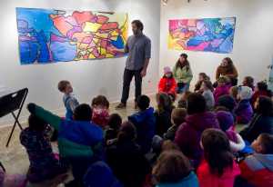 Brandon Howard, artistic coordinator for The Canvas, speaks to Harborview Elementary School kindergarteners as they see their work displayed in the gallery on Monday. About 50 students in teachers' Elisabeth Hauser and Maura Selenak classes made overlapping traces of their outlined bodies and then painted them with a mixture of primary colors. The work was an exercise in working together.