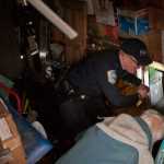 Sitka Police Lt. Lance Ewers shines a flashlight at the opening of a tunnel under a trailer in the Vitskari Trailer Park in Sitka, Alaska, Thursday, January 28, 2016, as he and the property's landlord, at right, inspect the property. A man wanted on criminal warrants was hiding under the trailer in what police called "an elaborate tunnel system." (AP Photo/Daily Sitka Sentinel, James Poulson)