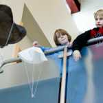 Auke Bay Elementary School fifth-graders Alex Filkov, right, and Kean Buss take turns releasing their parachutes during an class engineering project on Friday. The students learned the effects of canopy size, materials and suspension line length in making the best parachutes.