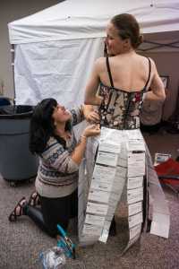 Artist Rosie Ainza fits model Marianna Carpeneti into her costume made of glass, synthetic leather, wire, ribbon and hateful public comments from social media users in her entry titled "Tweet" at the Wearable Art Extravaganza 2016 at Centennial Hall on Sunday.