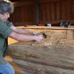 Sitka carver Tommy Joseph works on the beginnings of a canoe at Sitka National Historical Park, a project led by master carver Steve Brown. (National Park Service | Erin Fulton)
