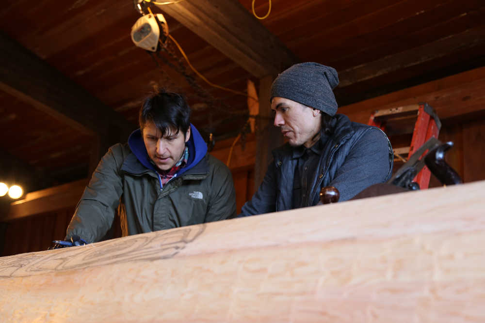 From left, Jerrod Galanin and TJ Young study the 28-foot red cedar log that will become a canoe. Jerrod and Nicholas Galanin's uncle and great grandfather were some of the last people to carve canoes in Sitka. (National Park Service | Erin Fulton)