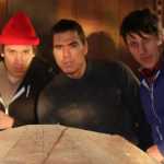 Three of the carvers working on the canoe are, from left, Nicholas Galanin, TJ Young and Jerrod Galanin. (National Park Service | Erin Fulton)