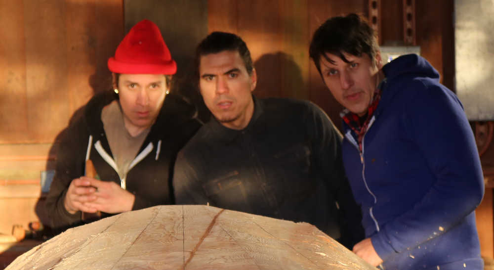 Three of the carvers working on the canoe are, from left, Nicholas Galanin, TJ Young and Jerrod Galanin. (National Park Service | Erin Fulton)