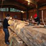 TJ Young, left, and Nicholas Galanin work on the beginning of the canoe. (National Park Service | Erin Fulton)