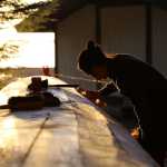 Haida carver TJ Young has been working on the canoe every day. All the carvers welcome visitors - and coffee. (National Park Service | Erin Fulton)