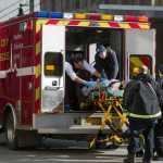 Juneau first-responders lift a woman onto an ambulance who reportedly shot herself in front of the main entrance of the Dimond Courthouse on Monday.