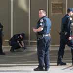 Juneau police officers collect evidence after a woman reportedly shot herself in front of the main entrance of the Dimond Courthouse on Monday.