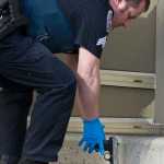 Juneau Police Department Sgt. Chris Gifford collects a handgun found at the scene where a woman reportedly shot herself in front of the main entrance of the Dimond Courthouse on Monday.