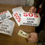 Ron Klein puts up signs in support of the weekly State of Alaska surplus sale Wednesday morning.