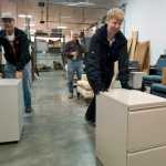 Joe and Stacey Thomas roll two filing cabinets to the cash register during the weekly State of Alaska surplus sale Wednesday morning.