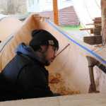 James (Gooch Éesh) Hart works on the inside of the first of two 40-foot spruce canoes. In the background is a log that will be used for the second canoe. Before the carvers began their work, the first log weighed 43,500 pounds, said master carver Wayne Price.