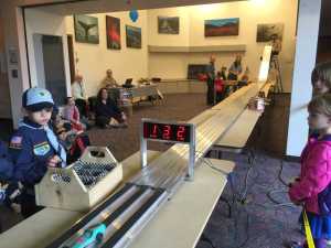 Pinewood Derby event took place at Centennial Hall. Participants look to the end of the derby track and the winning car.