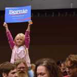 Five-year-old Courtney Skinner holds up a "Bernie Sanders for President" sign while sitting on Tom Skinner's shoulders at the Juneau Democratic Caucus on Saturday, March 26, 2016 in Centennial Hall's Sheffield Ballroom. Sanders won the majority of Juneau's votes and those across Alaska.