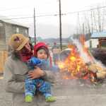 Ted and Adze Hart, who is seven months old, watch as the canoe is steamed. Ted is brother to apprentice James Hart, and came down from Haines with Meghan Elliott to participate in the final week of carving and the steaming. Adze danced and offered moral support as community members and carvers drummed.