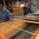 Melvin Williams measures the canoe. It expanded from around 37 inches at its widest point to around 59 inches before it developed a crack. Carvers are repairing the crack before they resume steaming. At his right are James Hart, Cherri Price, Wayne Price and Ted Hart. At the bottom of the canoe is ash from the heated rocks, which community members later washed out.