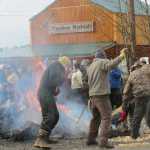 Zack James, James Hart and Herb Sheakley rake heated rocks out of the fire to place in the canoe.