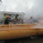Wayne Price directs Pete Schneeberger and Owen James on where to place the heated rocks in the canoe.