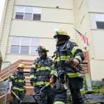 Firefighters leave the Channel View Apartments after clearing the building in response to a fire on the building's fifth floor.