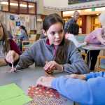 Harborview Elementary School fifth-graders Reece Hill, center, and Lauren Purves teach Pioneer Home resident Lenore Honsinger how to make paper cranes during a visit on Thursday.