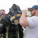 Dan Sprague, right, helps Dorion Hobbs, of S.E. Underwater Services, prepare for a dive to raise a 28-foot boat, above, that sunk at Don D. Statter Harbor in Auke Bay on Monday.