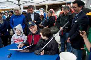 Gov. Bill Walker signs a bill creating an Alaska Salmon Day with the help of Maverick Sprague, 5, left, and his brother, Oden, 6, during the Juneau Maritime Festival at Marine Park in Juneau on Saturday, May 7, 2016.