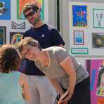 Juneau schools arts specialist Nancy Lehnhart, 51, talks with Delphine Hochstoeger, 6, about art as her father Peter looks on at the 14th annual UAS Community Day on Saturday.