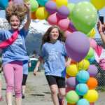 Neeva Cole celebrates with her friend Hanna Mcnaughton as they finish during the Girls on the Run fun run event Saturday morning at Riverbend Elementary.