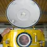 Faith Community Christian School third-grader Gunnar Tarver peeks out a porthole window of a one-person training submarine at the Auke Bay Fire Station on Tuesday.