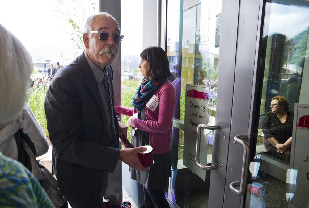 Bob Banghart, deputy director of the State Libraries, Archives and Museums unrolls a red ribbon during the Grand Opening of the Fr. Andrew P. Kashevaroff building housing the State Library, State Archives and State Museum on Monday.