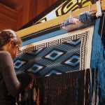 Gabby Kay shows how she helps her mother, Shgen George, weave during the Ravenstail and Chilkat Weaver Symposium at the Walter Soboleff Building's clan house Wednesday.