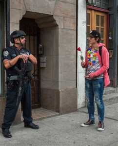 In this June 12 photo, a heavily armed police officer stands guard in New York's Greenwich Village neighborhood as a man arrives to the makeshift memorial near the Stonewall Inn for the victims of the mass shooting in Orlando, Florida.