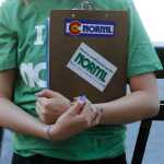 In this June 11 photo, a marijuana reform advocate with the group NORML holds a clipboard while waiting for passersby to sign a petition to get a pot club initiative on the ballot in the next election, in Denver.