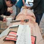 Elijah Marks, left, Fred Fulmer, center, and Sam Sheakley work off a design by master carver Nathan Jackson of Ketchikan on a 25-foot Raven pole at Harborview Elementary School on Wednesday.