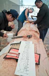 Elijah Marks, left, Fred Fulmer, center, and Sam Sheakley work off a design by master carver Nathan Jackson of Ketchikan on a 25-foot Raven pole at Harborview Elementary School on Wednesday.
